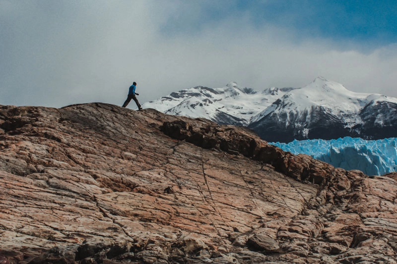 Rafa caminhando no topo de montanha, com Perito Moreno ao fundo