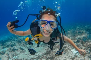 Mergulhadora sorrindo debaixo d'água após mergulho em Cozumel