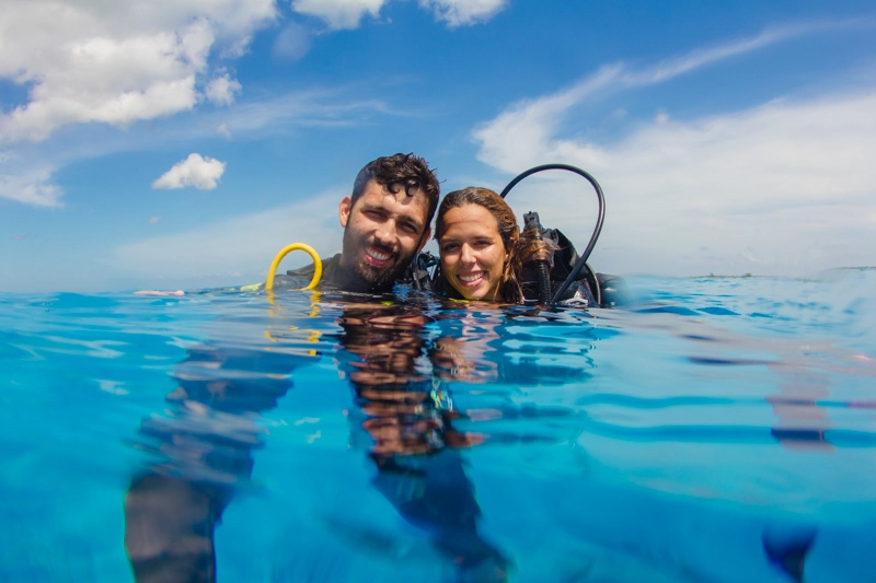 Casal com equipamento de mergulho na superfície do mar azul turquesa de Cozumel