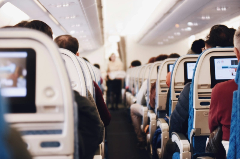 Interior de um avião, com passageiros sentados em suas poltronas