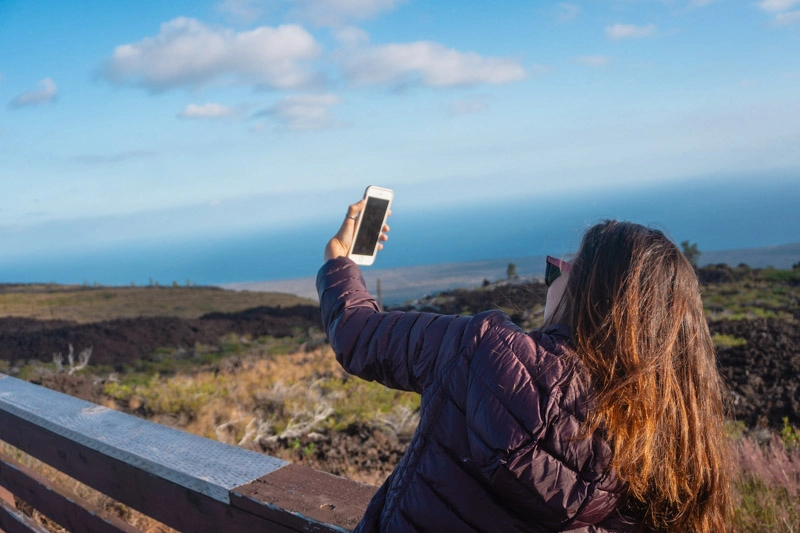 Tata segurando celular em modo selfie, em Big Island, no Hawaii