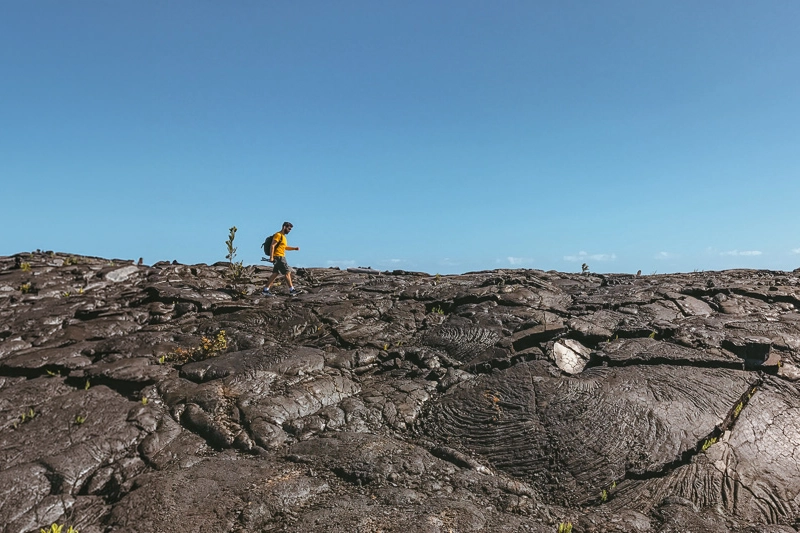 Trilha em um solo cheio de pedras vulcânicas para chegar à Kaimū Black Sand Beach