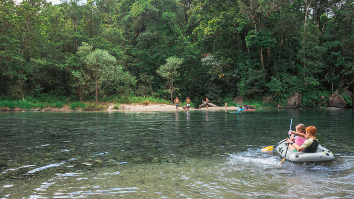 Crianças em bote inflável na piscina formada pela Babinda Boulders, em Cairns, na Austrália. Muita árvore e muito verde em volta.