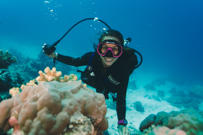 Mergulhadora sorrindo e segurando o regulador com a mão