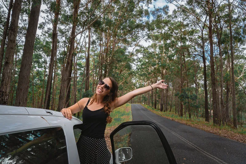 Mulher em campervan em estrada arborizada na Australia