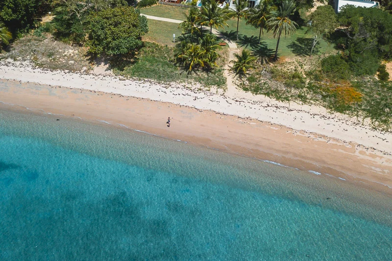 Vista aérea de uma praia de Magnetic Island, com faixa de areia clara e mar azul-turquesa.