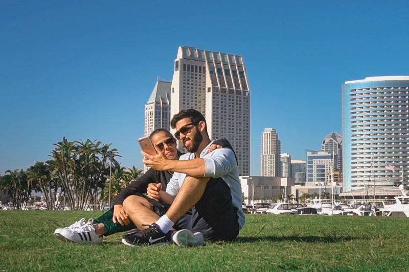Tatá e Rafa usando celular em San Diego, na Califórnia. Estar conectado facilita o uso dos serviços do celular durante uma viagem internacional.