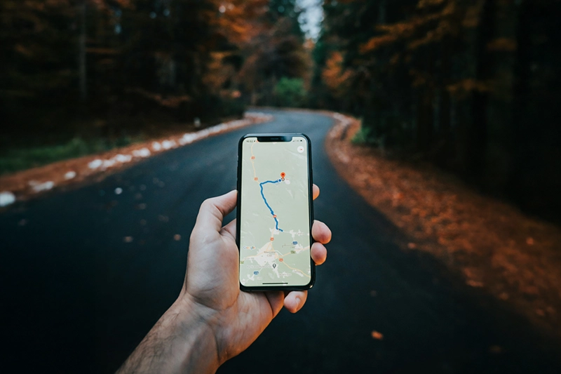 No caminho de uma trilha, tela de celular exibindo um mapa com rota traçada. Ter internet no celular é importante para se localizar em um destino desconhecido.