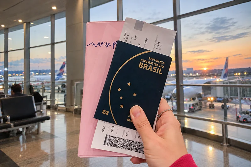 Passaportes e cartões de embarque nas mãos de uma viajante no aeroporto.